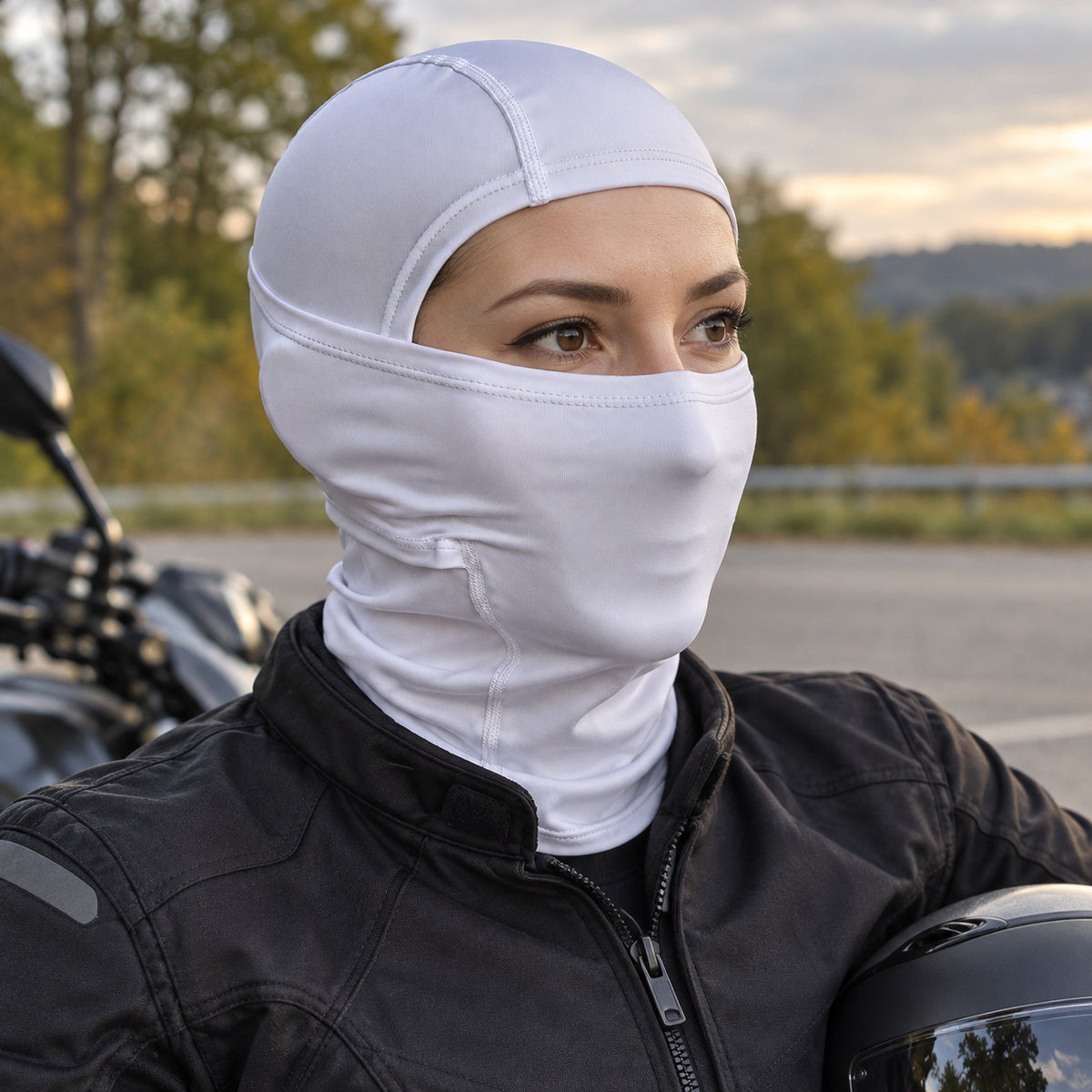 Motorradfahrerin mit weißer PIXLII Allseason Sturmhaube und Motorradhelm neben einem geparkten Motorrad